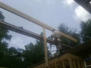Carpenter setting a ridge beam over a new addition frame — Ice Dam Removal by Roofing Brothers in Quinton
