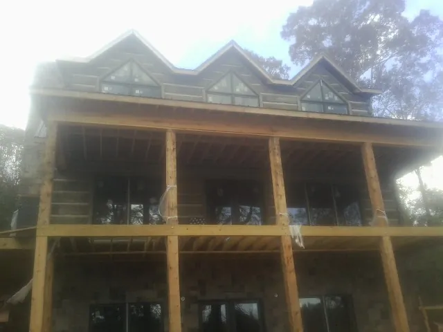 Dormers and porch framing on a large log home under construction — Roof Coating work by our crew in Quinton