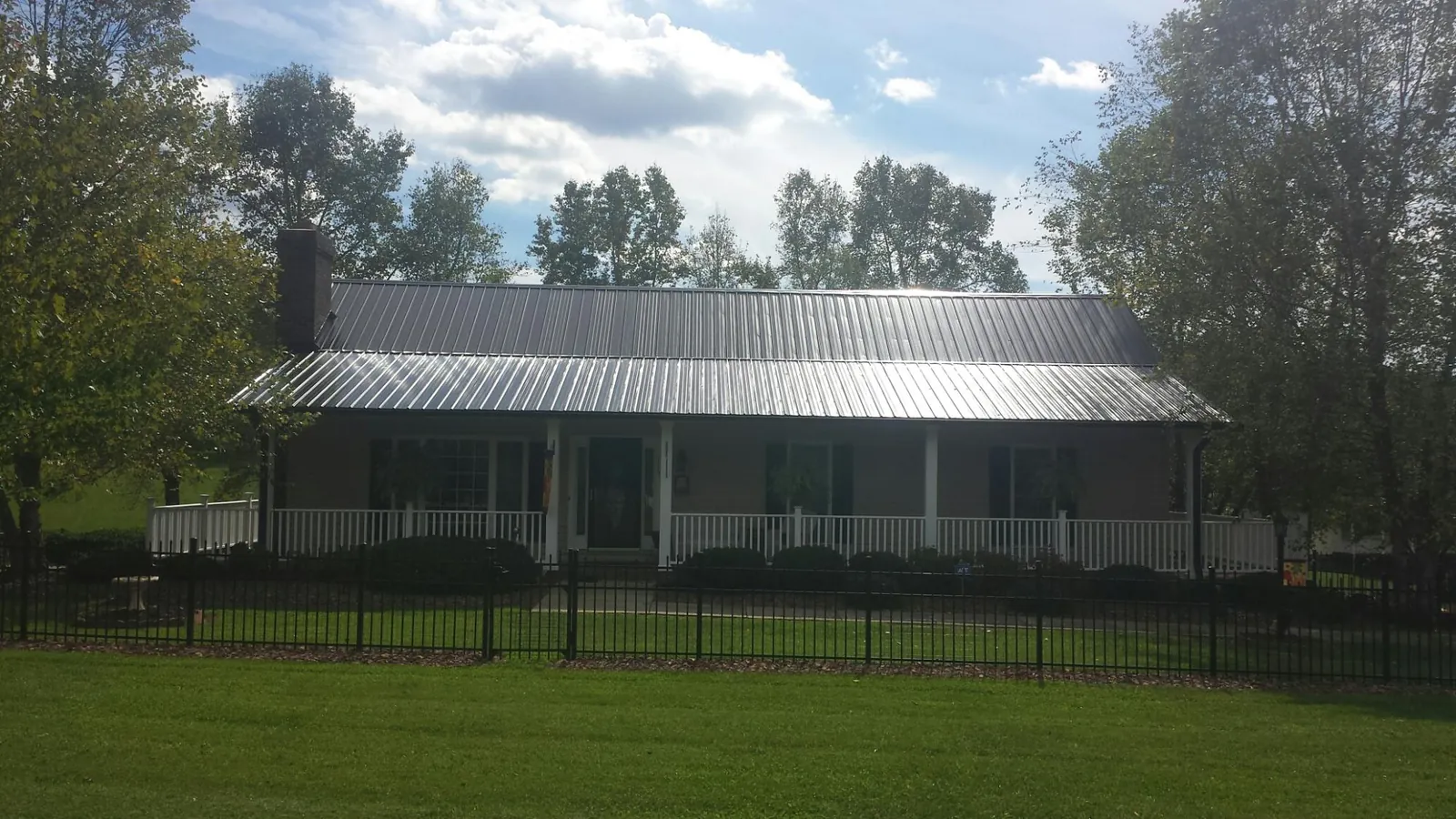 Gray metal roof on a brick ranch with a full width front porch — Gutter Guard Installation work by our crew in Quinton