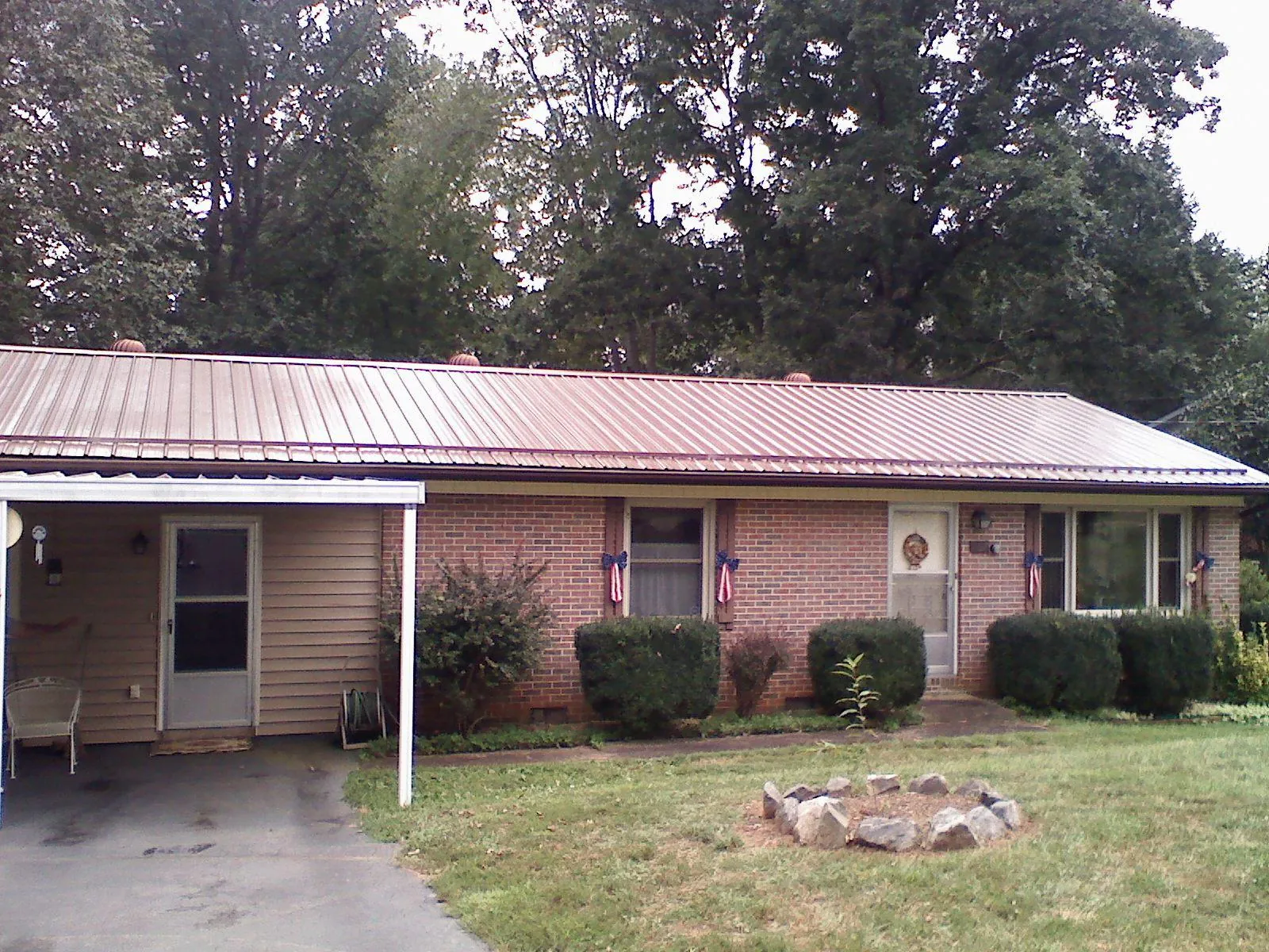 Bronze metal roof and carport on a brick ranch home — Roof Repair work by our crew in Quinton